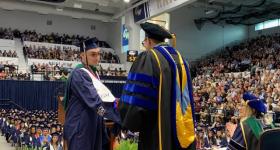 Faculty handing a student their diploma 
