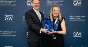 Scott McIntyre, Guidehouse CEO, accepting Don Strong Community Partner of the Year Award from Dean Lynn Goldman at the Milken Institute School of Public Health Community Partner Appreciation Event