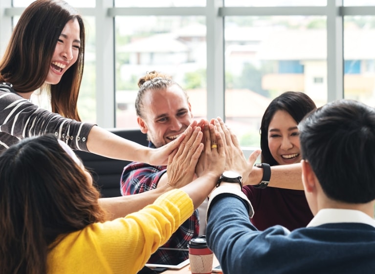 group of adults putting their hands together