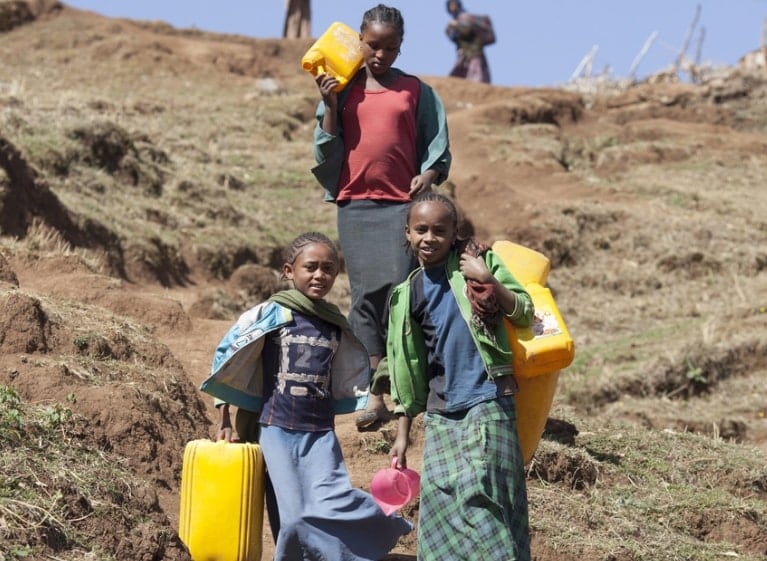 three children carrying containers outside