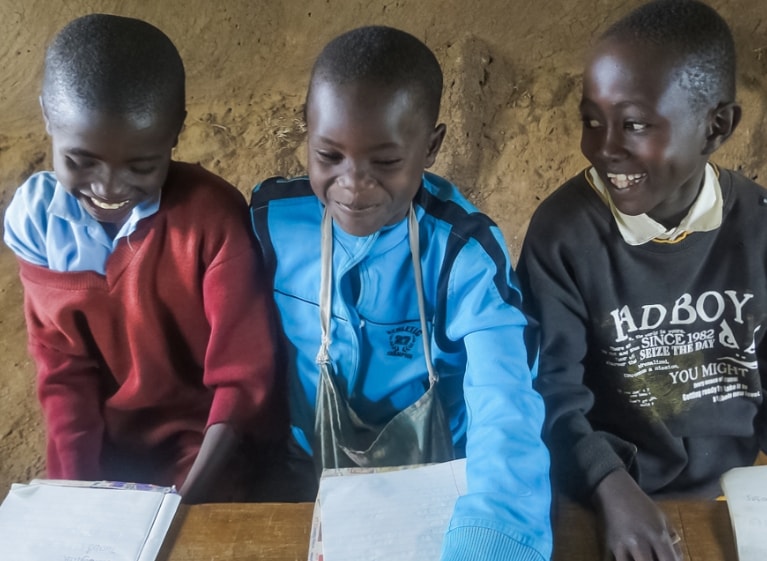 three smiling children with notebooks