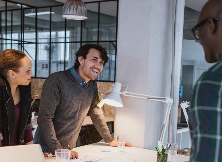 Three adults smiling around a desk