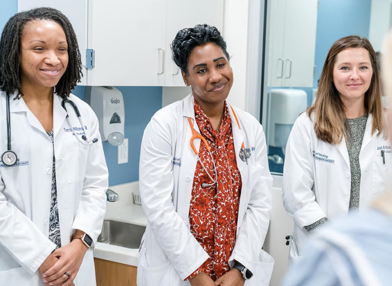 Three smiling women wearing lab coats