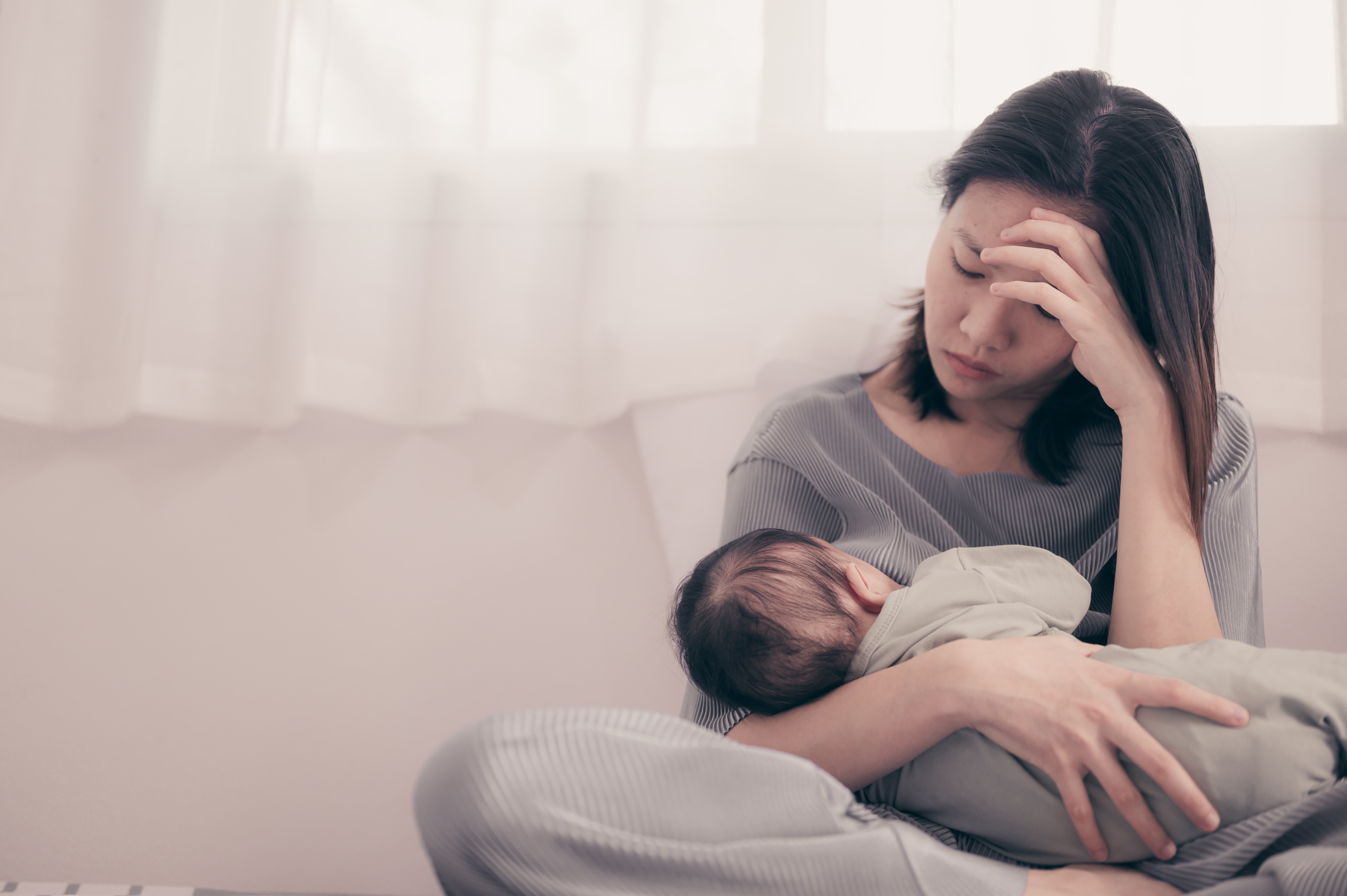 Woman looking sad while holding a baby