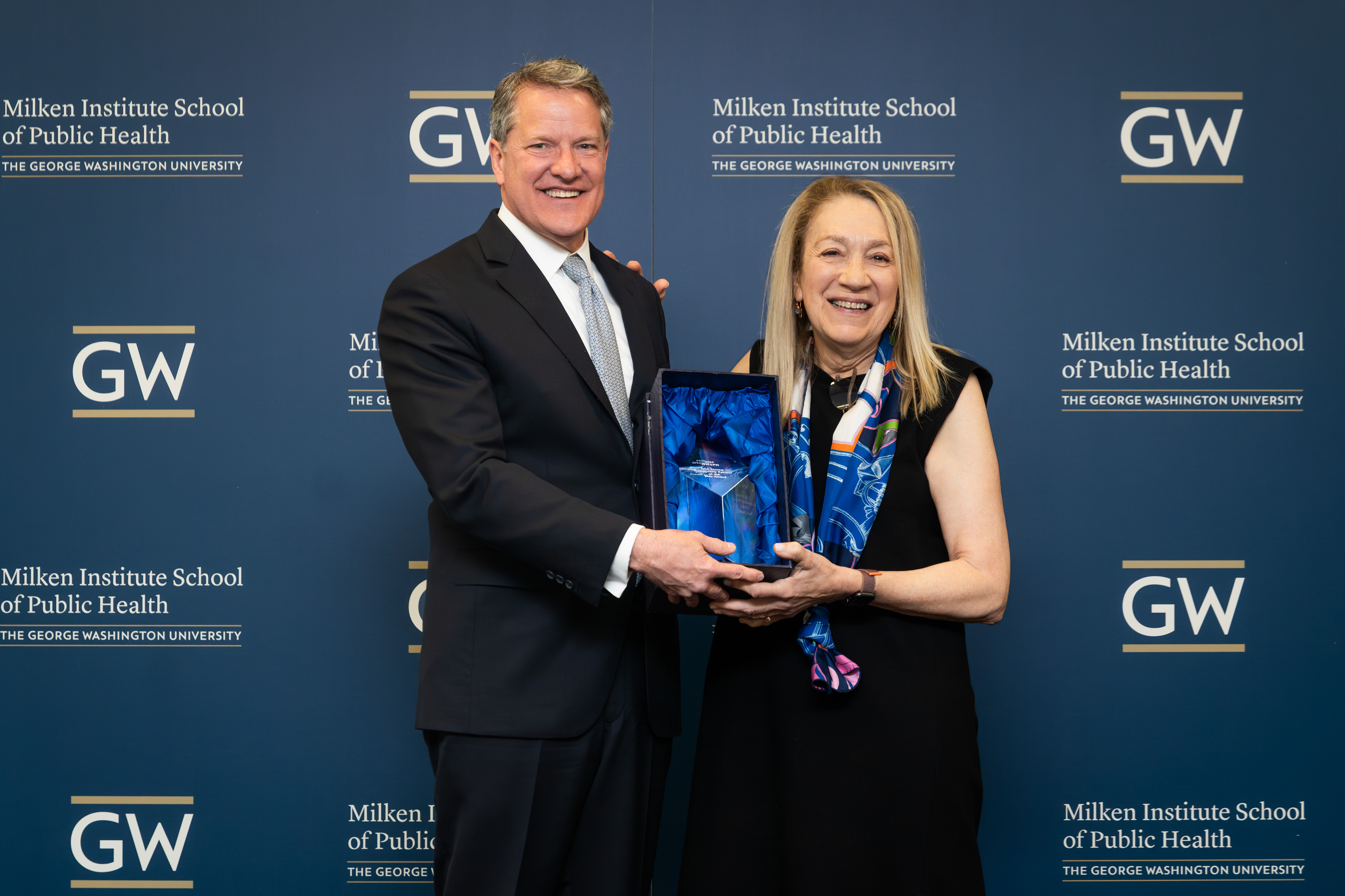 Scott McIntyre, Guidehouse CEO, accepting Don Strong Community Partner of the Year Award from Dean Lynn Goldman at the Milken Institute School of Public Health Community Partner Appreciation Event