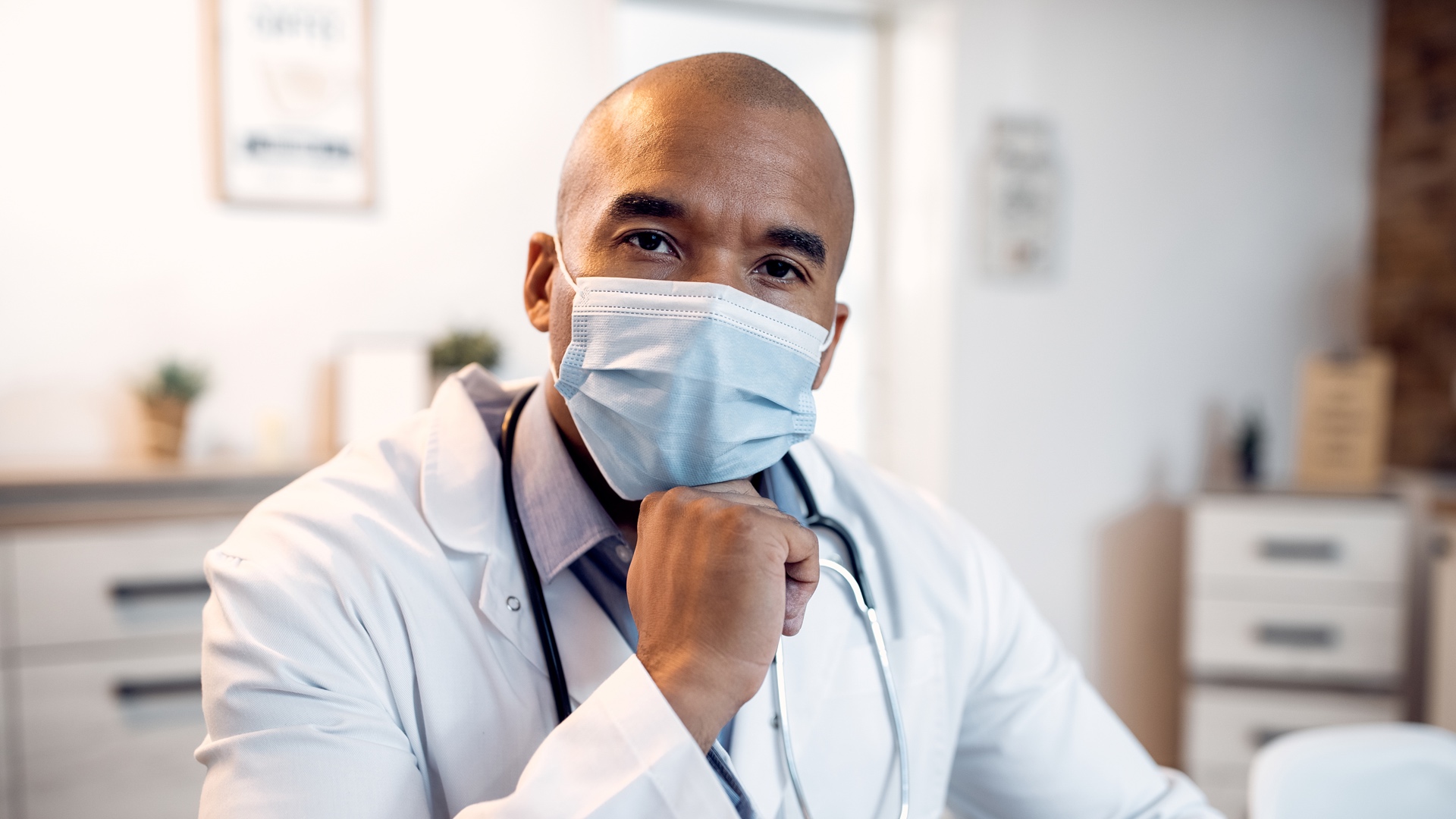 Male black doctor wearing a mask looking at the camera