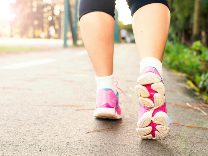 The back of someone's legs wearing sneakers and walking.