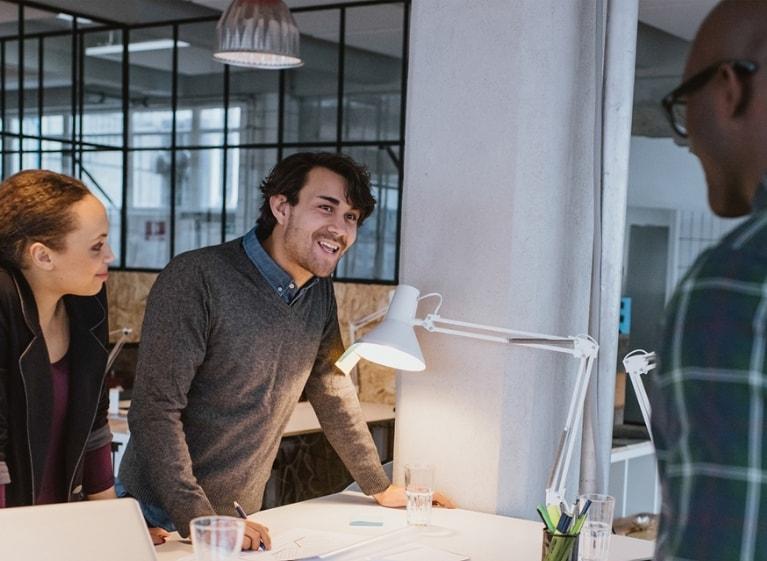 Three adults smiling around a desk