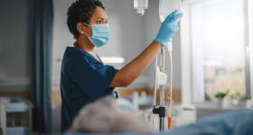Female, black health care worker with an IV bag