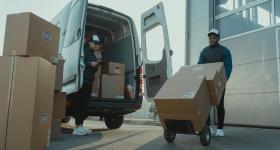 Two workers unloading boxes from a van.